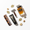 Men's grooming kit flat lay with razor, cologne, moisturizer, and styling comb
